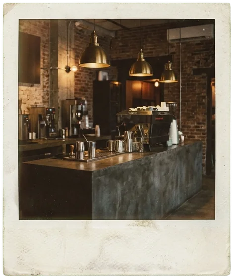 An instant photo of the concrete coffee bar under brass pendant lamps