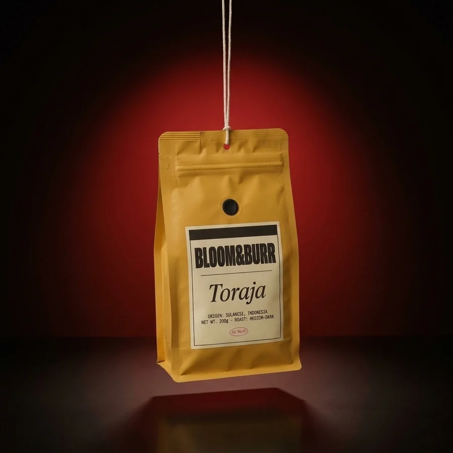 A mustard Toraja pouch hanging from a cotton string in a red glow over a dark glossy floor